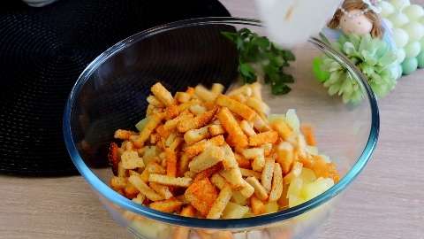 Сухарики со вкусом колбасы в миске с ингредиентами для салата